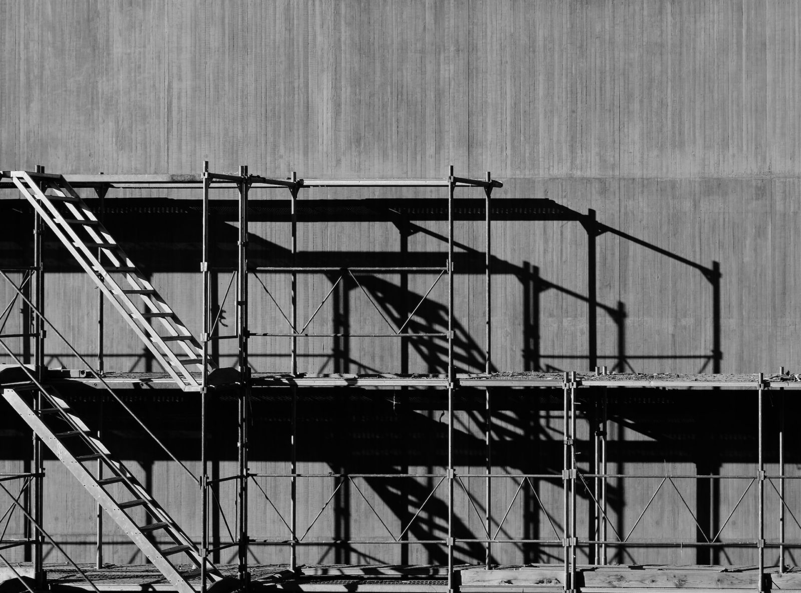 black and white image of scaffolding against a wall